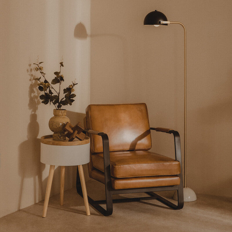 Brown leather armchair in a room with a side table and lamp.