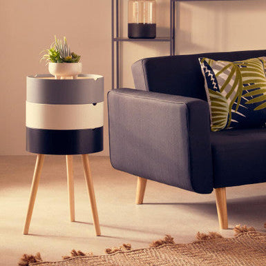 Modern living room with a striped side table and gray sofa.