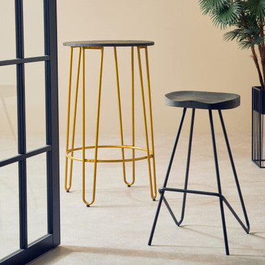 Two bar stools, one with gold legs and the other with black legs, against a beige wall.