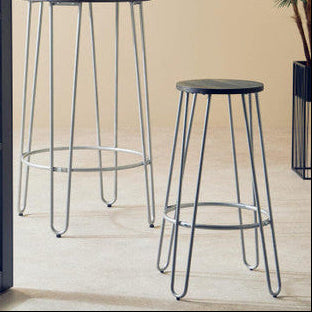 Two bar stools with metal legs and wooden seats in a room with a plant and window.