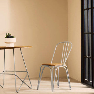 Dining area with a wooden table and metal chair against a beige wall.