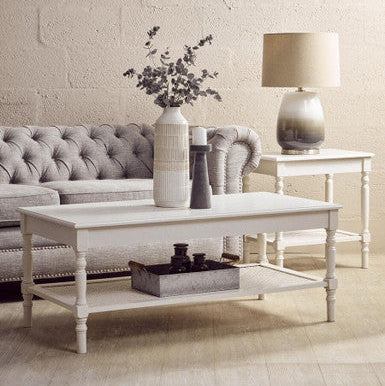 Living room with gray tufted sofa, white coffee table, and decorative items.