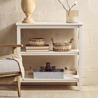 White side table with lamp, baskets, and decor against a beige wall