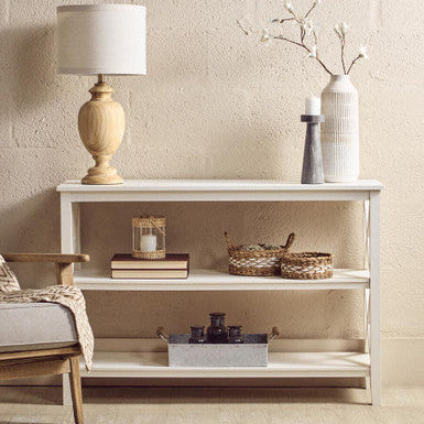 White console table with decorative items against a beige wall