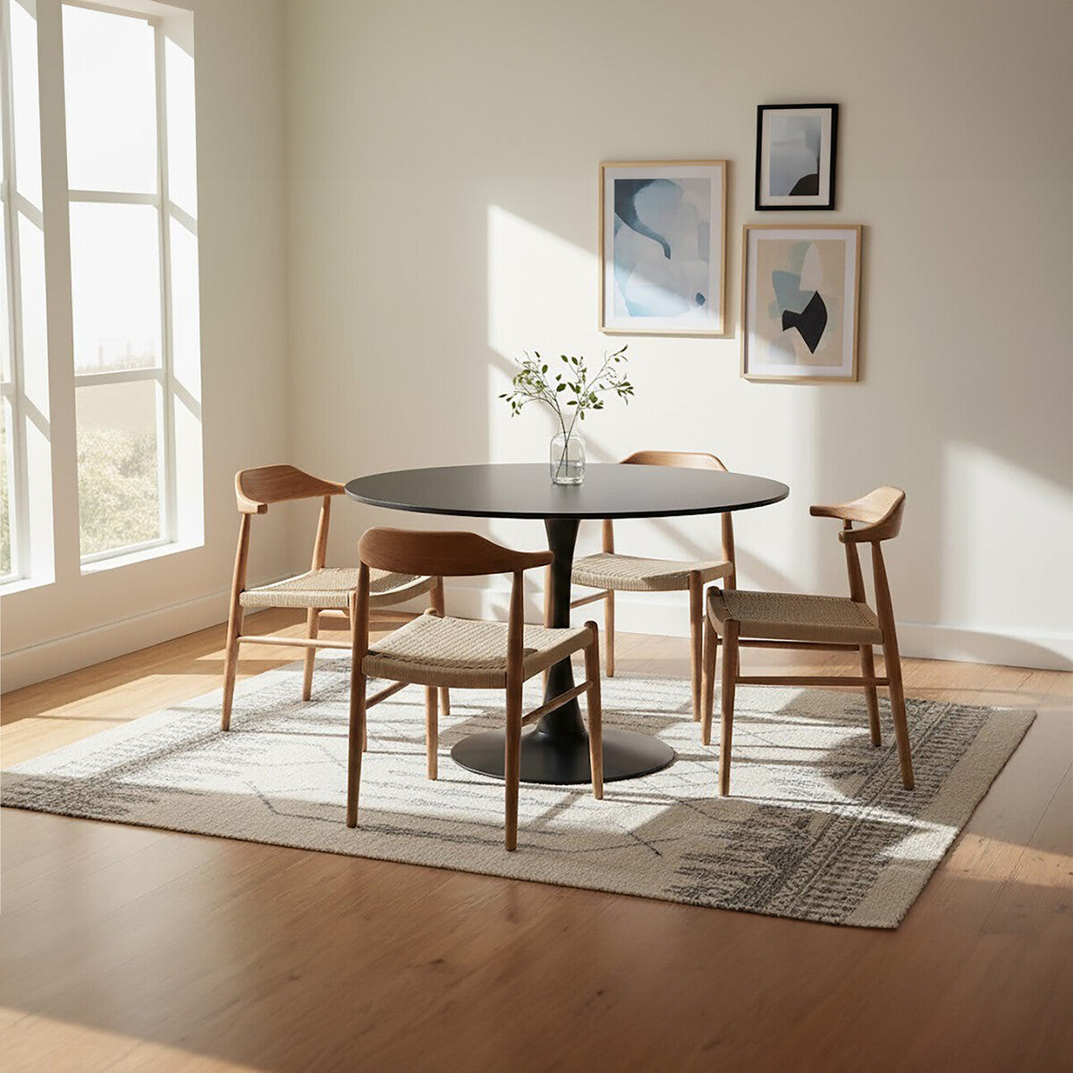 Dining room with a round black table and wooden chairs, light-colored walls, and large windows.