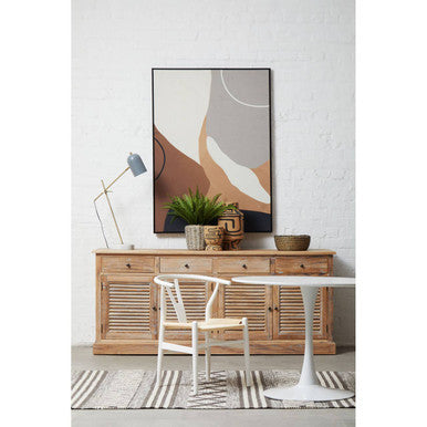 Modern interior with a wooden sideboard, white chair, and abstract art on a white wall.