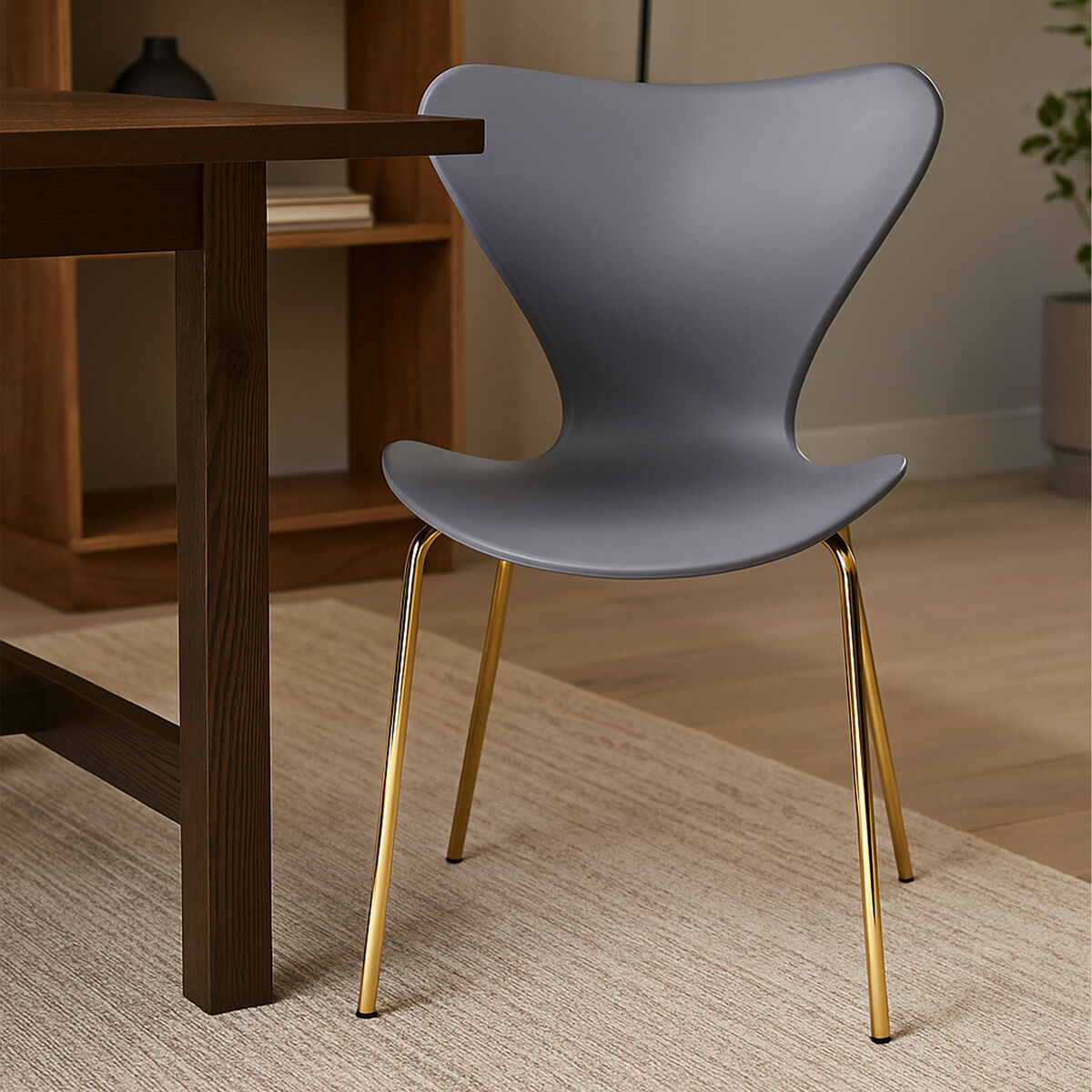 Gray chair with gold legs next to a wooden table in a room setting.