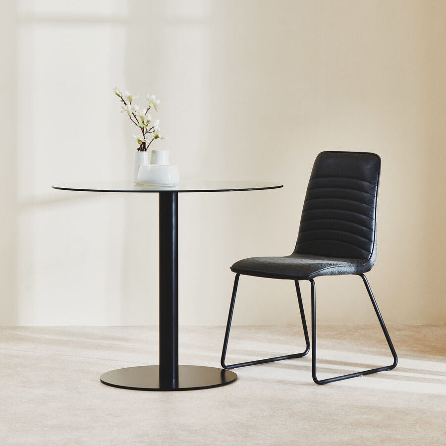 Black chair and table set against a beige wall