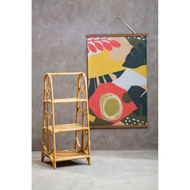 Rattan bookshelf next to a colorful abstract painting on a gray wall.