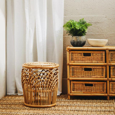 Wicker basket and dresser with plant against white curtain
