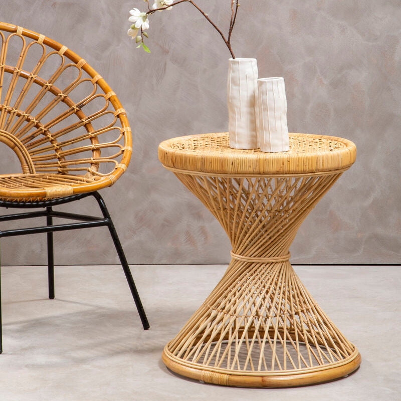 Wicker side table with a vase and branch against a gray wall