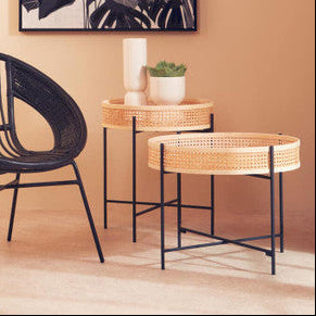 Black wicker chair and side table with a plant against a beige wall