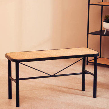 Wooden bench with black metal frame against a beige wall