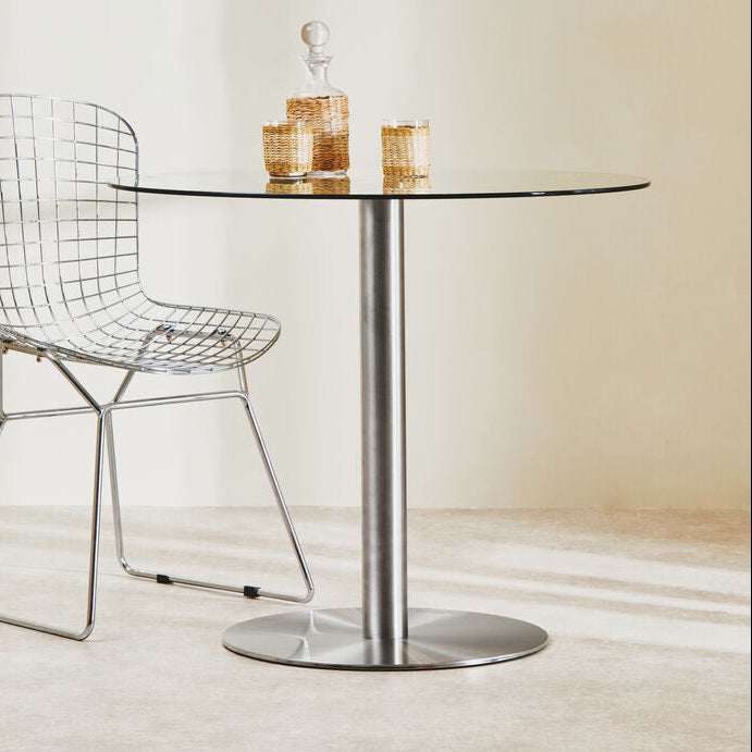 Modern wire chair and glass table with candles on a neutral background