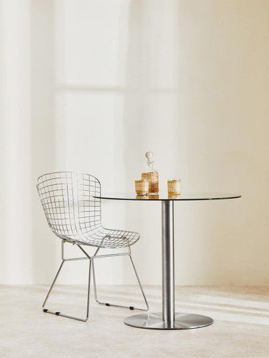 Modern wire chair and glass table against a neutral background