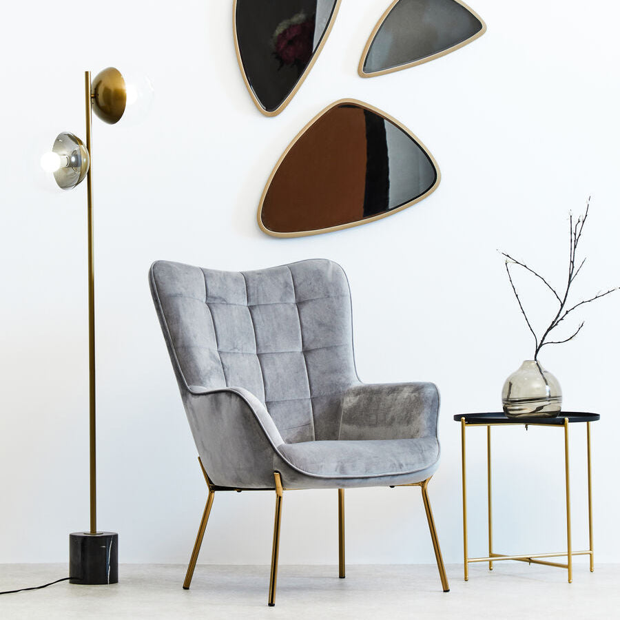 Modern interior with a gray armchair, wall art, and side table.