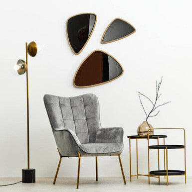 Modern interior with a gray armchair, gold floor lamp, and decorative wall art.