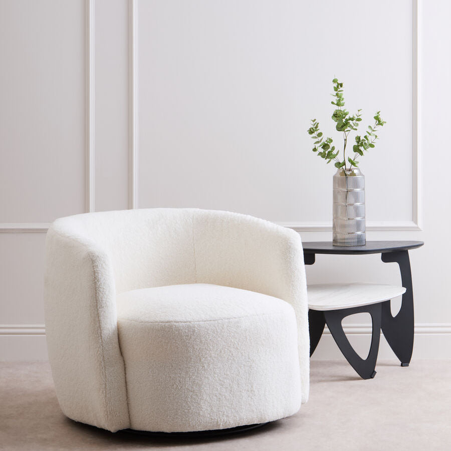 White armchair in a minimalistic room with a small table and plant.