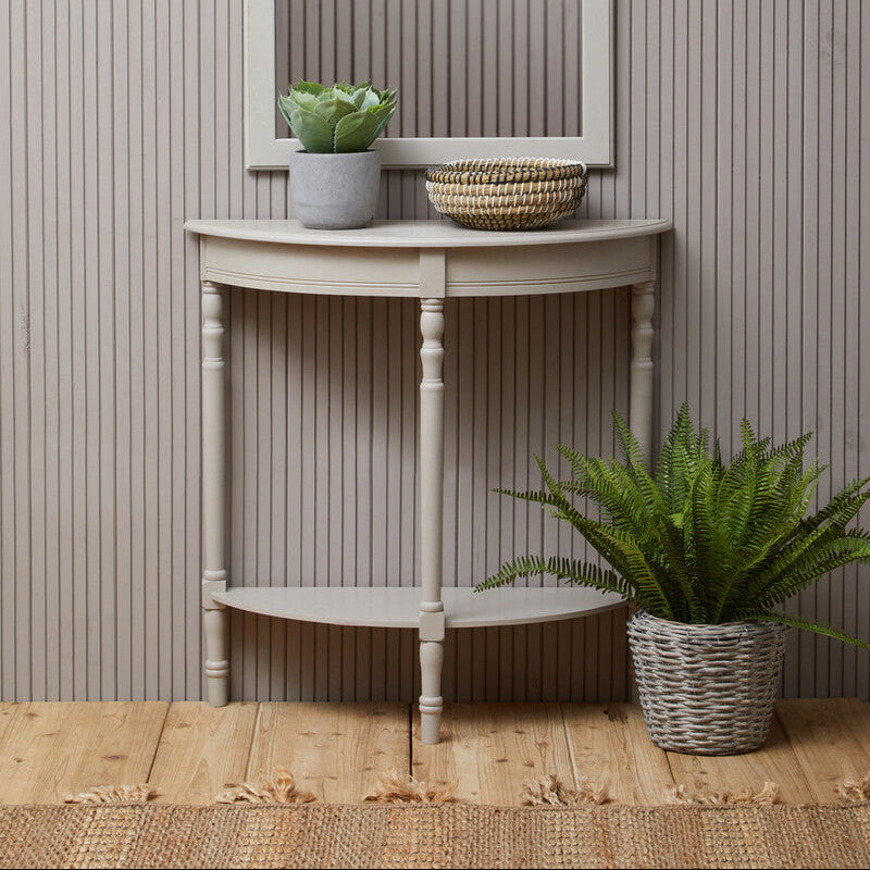 Small wooden console table with a mirror, plants, and a basket against a striped wall.