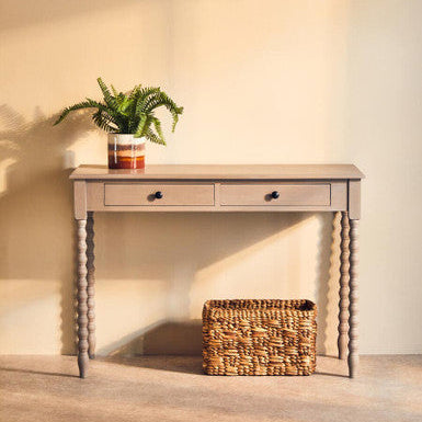 Wooden console table with a plant and basket against a plain wall