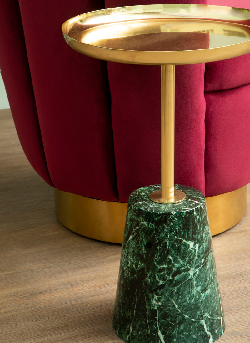 Gold side table with green marble base in front of a red upholstered chair.