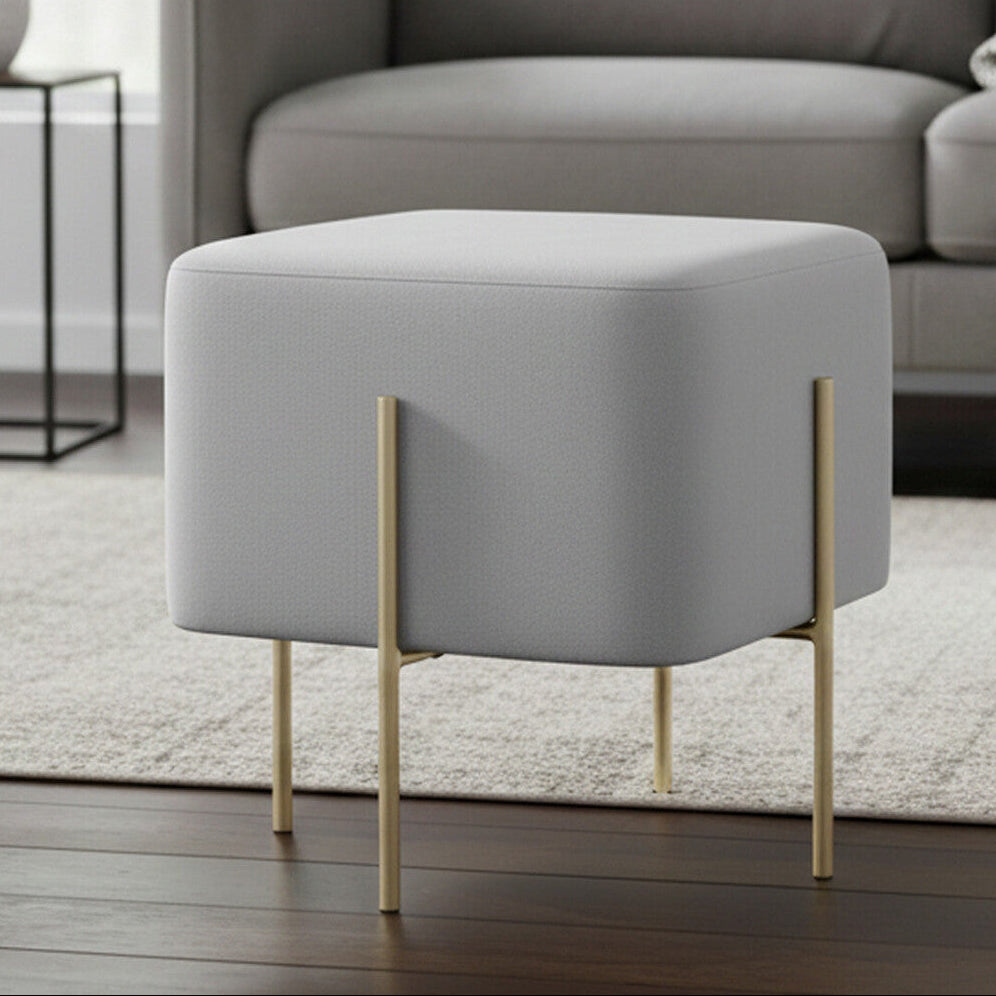 Gray ottoman with gold legs in a living room setting