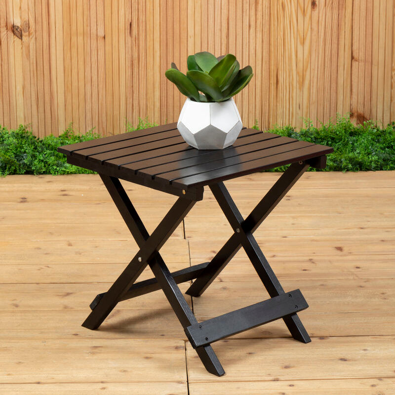 Black folding table with a plant on a wooden deck against a wooden fence.