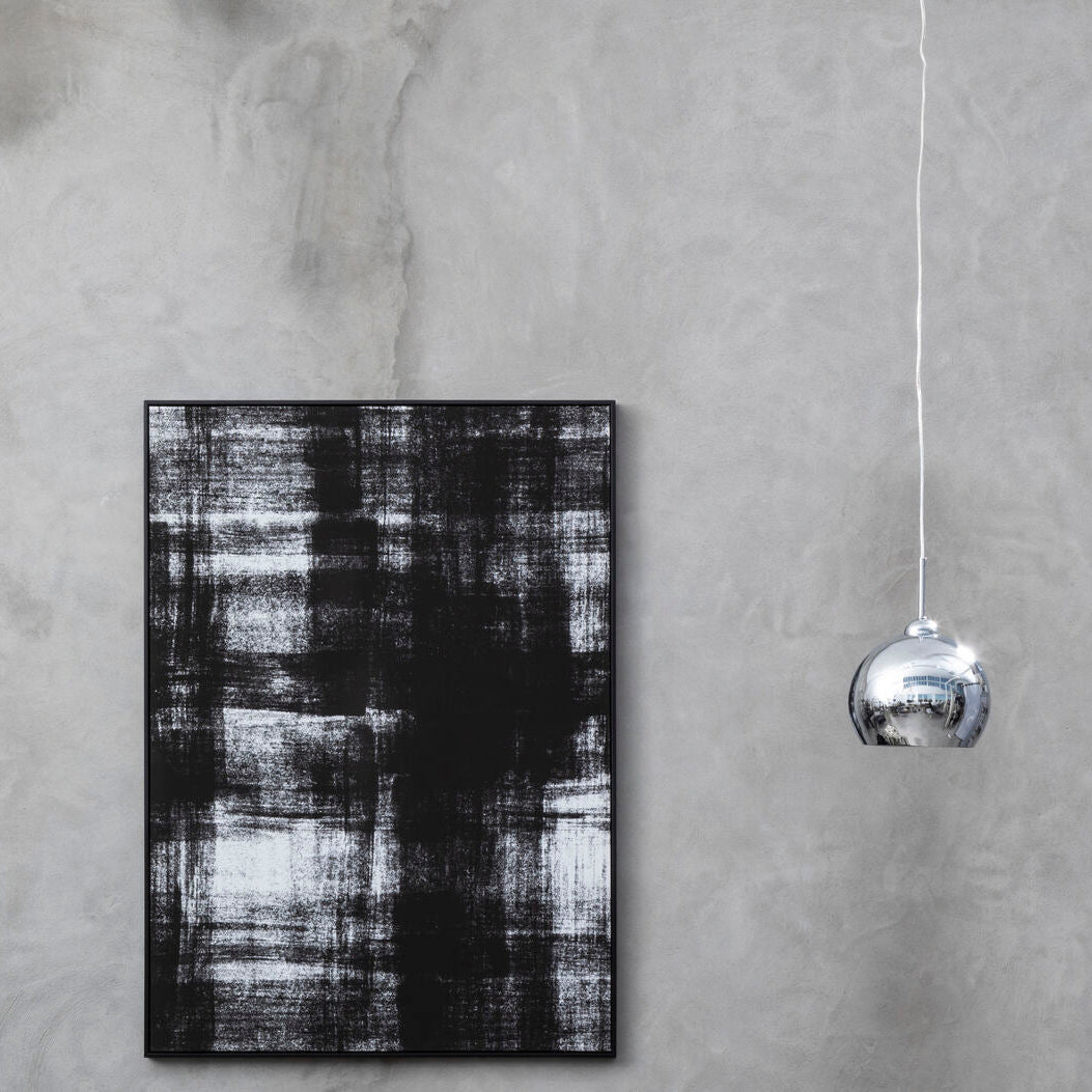Abstract black and white painting on a textured gray wall with a hanging silver sphere.