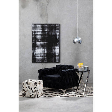 Modern living room with black sofa, abstract painting, and decorative items.