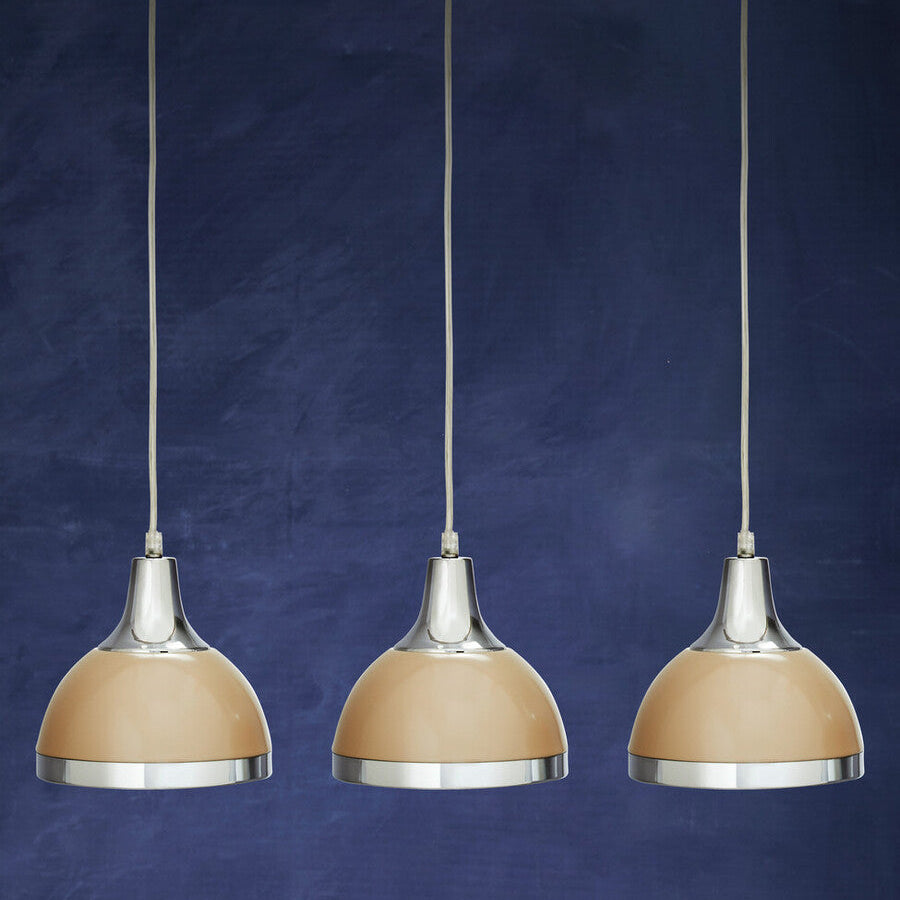 Three pendant lights with beige shades and silver bases on a blue background
