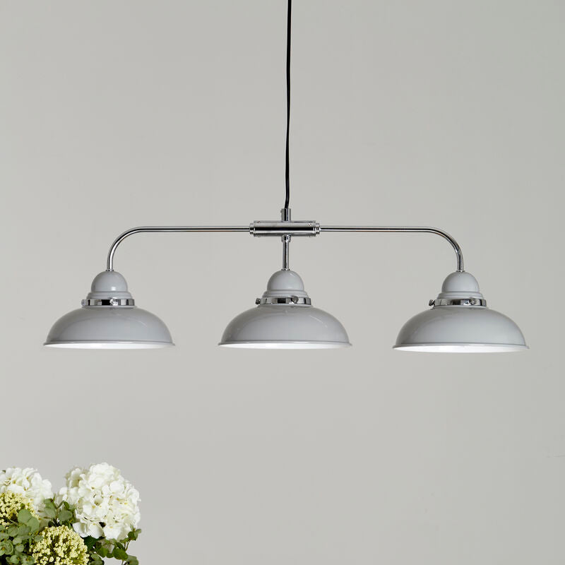 Three-bulb pendant light fixture on a wooden surface with a neutral background