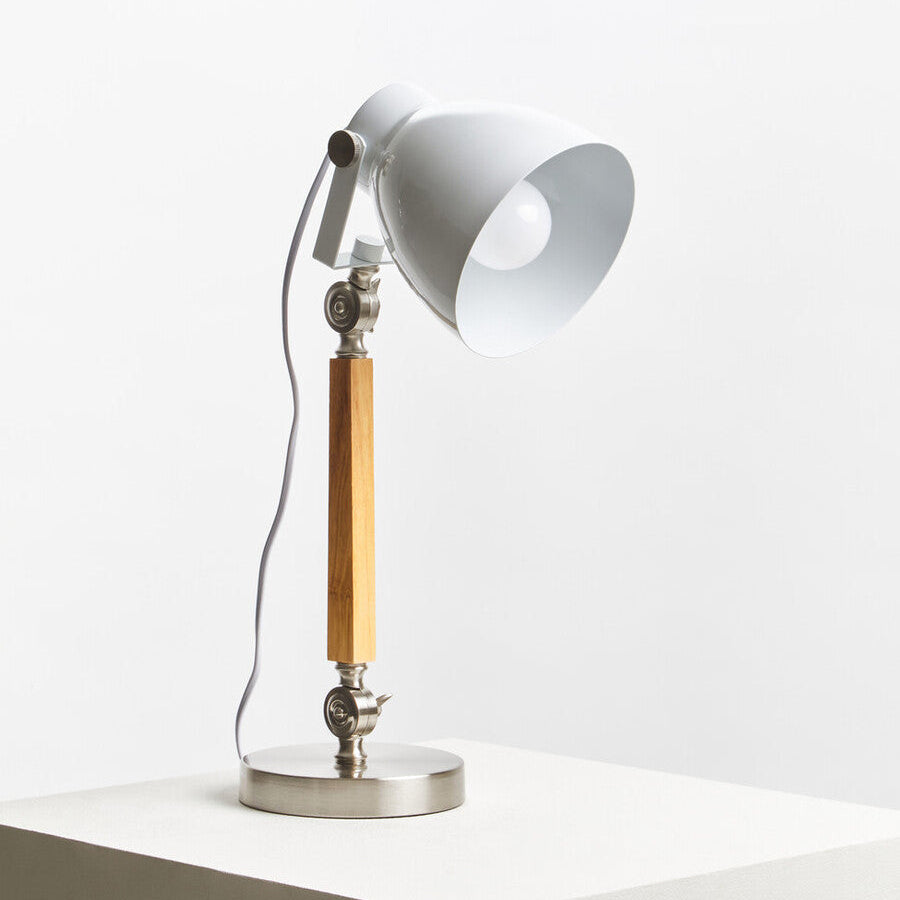 Table lamp with white shade and wooden arm on a white surface