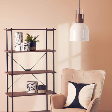 Beige armchair with a decorative pillow next to a wooden shelf against a beige wall.