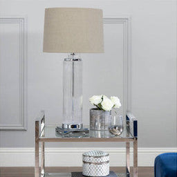 Modern side table with lamp and decor items against a gray wall.