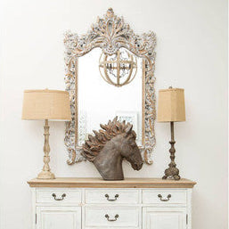 White sideboard with wooden top, decorative mirror, and lamps against a white wall.