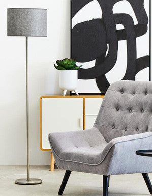 Gray armchair in a modern living room with abstract art and floor lamp.
