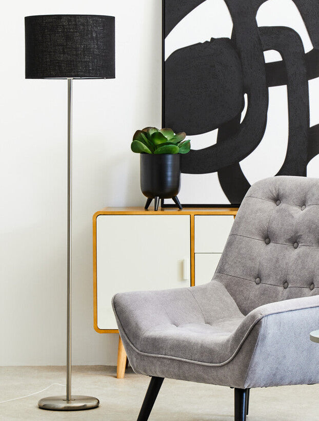 Gray armchair in a modern living room with abstract art and floor lamp.