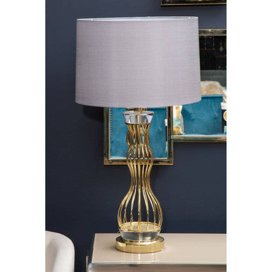 Decorative table lamp with gold base and gray shade on a white surface.