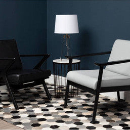 Two armchairs in a living room with a geometric rug and a lamp.