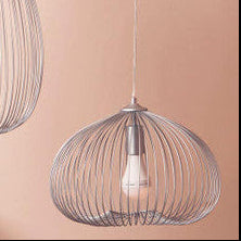 Two wire pendant lights hanging against a pink wall with a table and decorative items below.