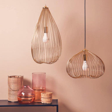 Two wire pendant lights hanging against a pink wall with decorative vases on a table.