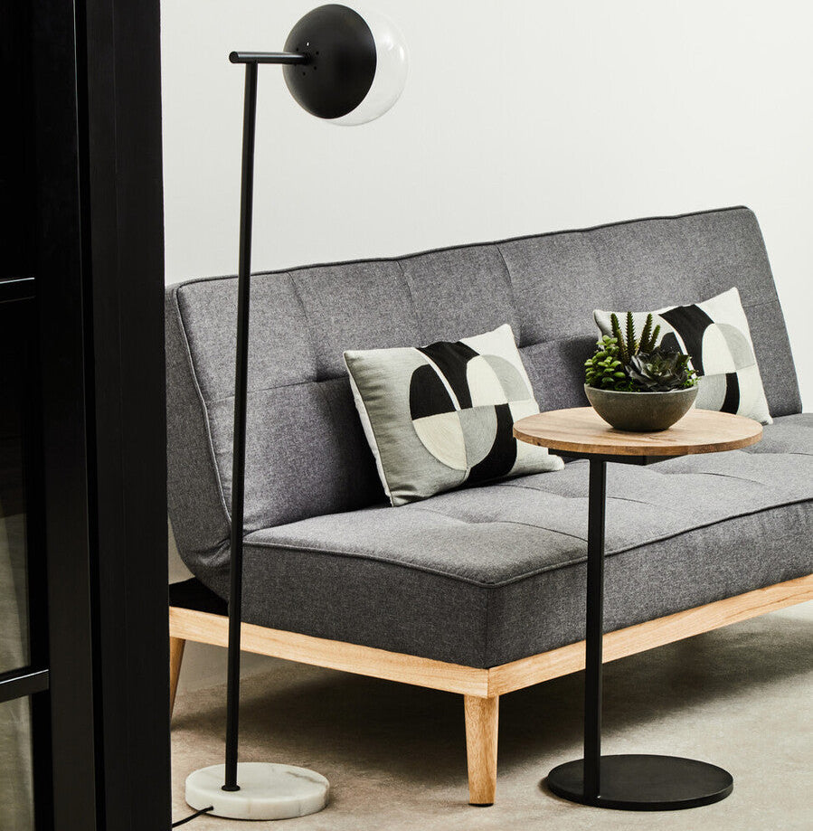 Gray sofa with decorative pillows and a small round table in a modern living room setting.