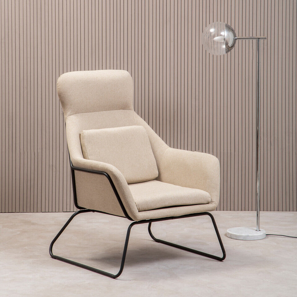 Beige armchair with black metal frame against a striped wall.