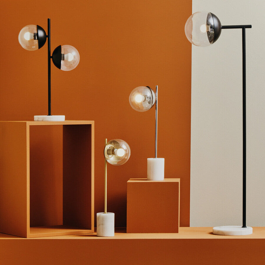 Modern table lamps on orange and beige geometric shapes against a gradient wall.