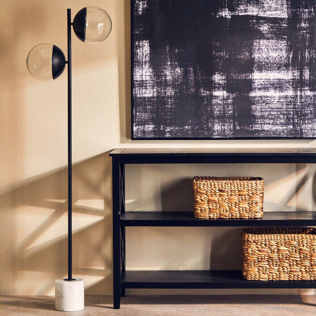 Modern interior with a black console table, abstract painting, and floor lamp.