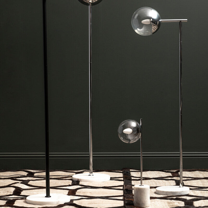 Set of modern floor lamps with metallic shades on a patterned floor against a dark wall.