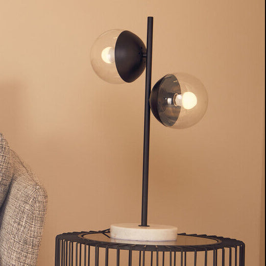Modern living room with a gray sofa, decorative pillow, and a black wire side table with a lamp.