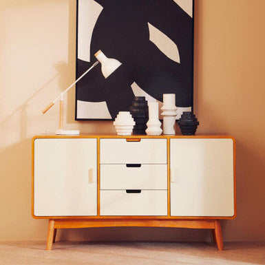 Wooden sideboard with decorative items and abstract art on a beige wall