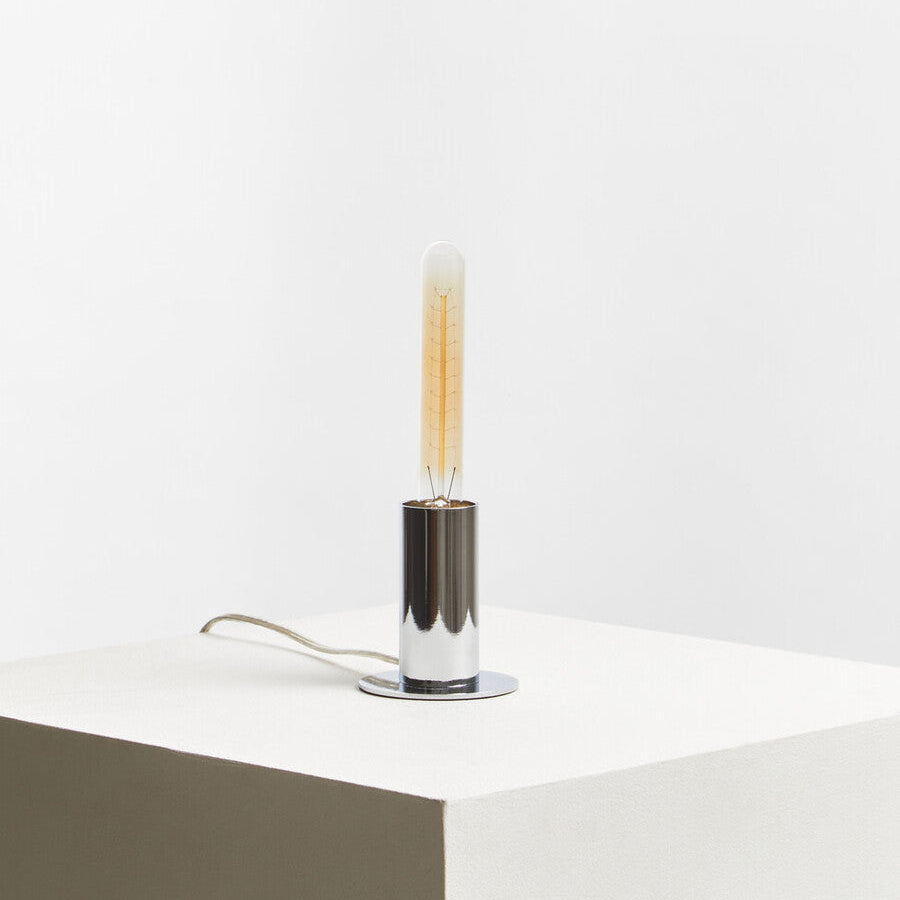 Modern table lamp with a cylindrical design on a white surface.