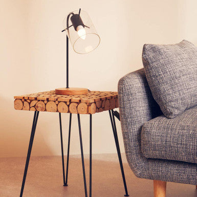 Small side table with woven top and black metal legs next to a gray sofa.